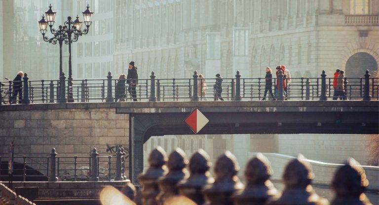 Piétons traversant un pont historique en pierre dans une ville européenne