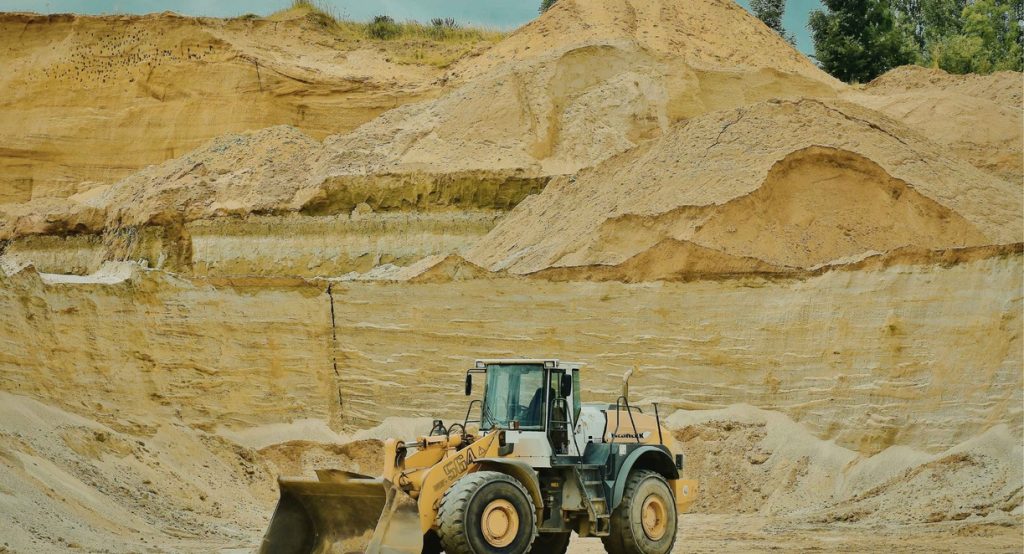 Chantier de construction avec bulldozer et tas de sable illustrant le poids d'un mètre cube