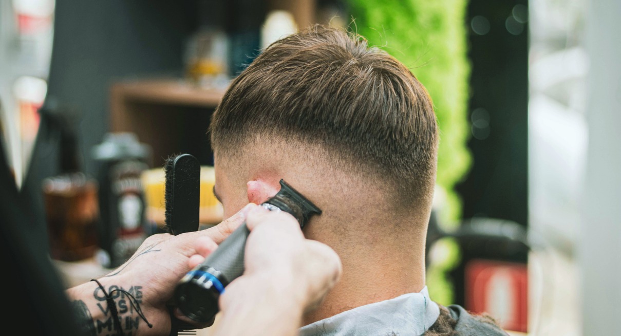 Barbier réalisant une coupe de cheveux dégradée à la tondeuse