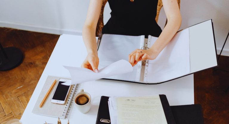 Personne classant des documents administratifs dans un classeur sur un bureau