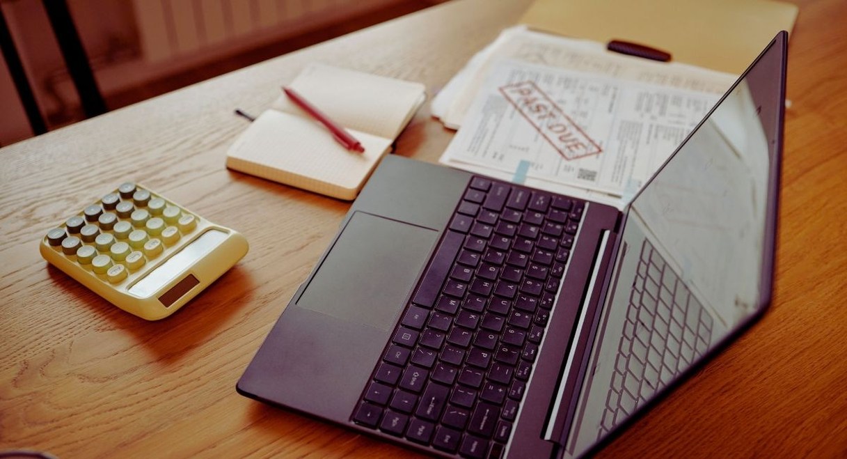 Facture en retard de paiement posee sur un bureau a cote d un ordinateur portable et d une calculatrice